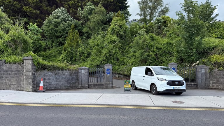 White Bear Services van parked at entrance gate with stone walls and traffic cone, surrounded by green trees