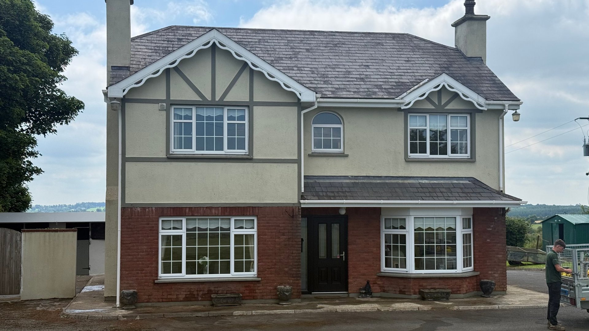 Two-story suburban house with red brick lower level, cream upper level with timber detailing